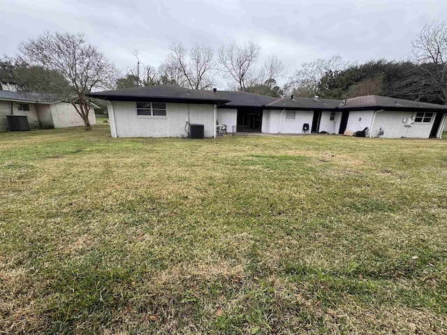 back of property featuring cooling unit and a lawn