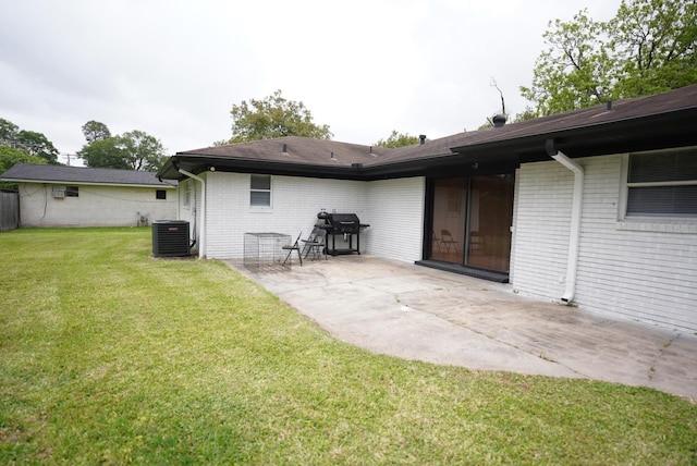 back of house featuring a lawn, brick siding, central AC, and a patio