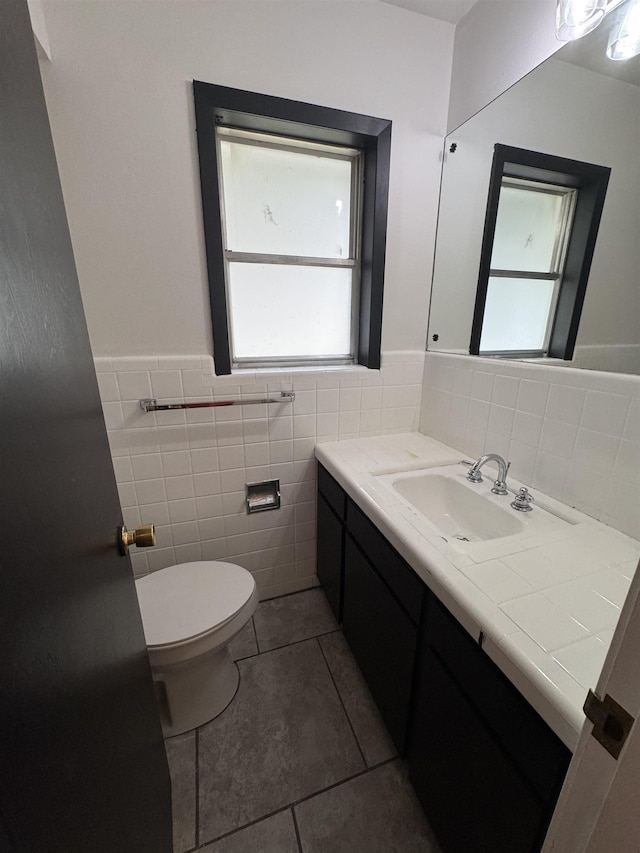 bathroom featuring toilet, tile patterned flooring, tile walls, and vanity