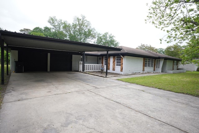 prairie-style house with concrete driveway, brick siding, a carport, and a front yard