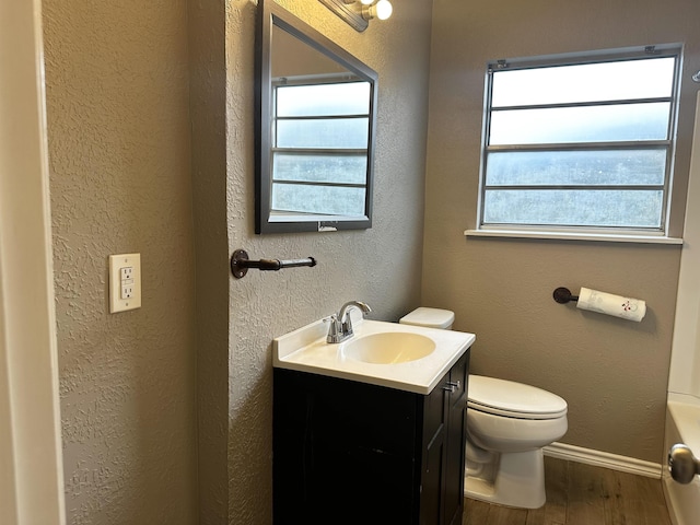 7165 Lewis Dr, Beaumont, TX 77708 - bathroom with wood finished floors, vanity, toilet, baseboards, and a textured wall