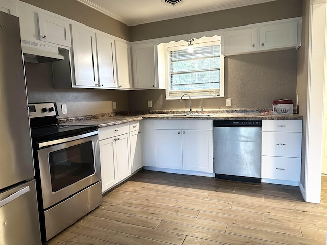 7165 Lewis Dr, Beaumont, TX 77708 - kitchen featuring appliances with stainless steel finishes, a sink, under cabinet range hood, ornamental molding, and light wood-type flooring