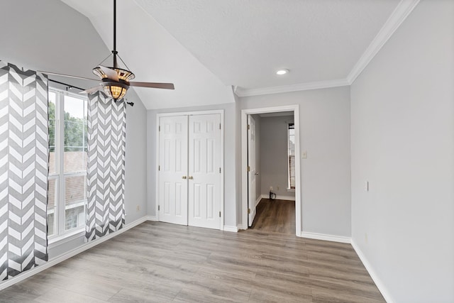 unfurnished bedroom featuring lofted ceiling, light hardwood / wood-style flooring, ceiling fan, and crown molding