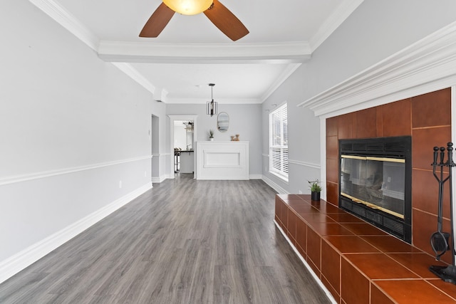 unfurnished living room featuring ceiling fan, dark hardwood / wood-style floors, crown molding, and a tiled fireplace