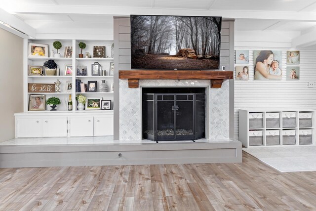 interior space featuring built in shelves, wood-type flooring, and a tile fireplace