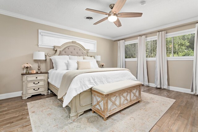 bedroom with ceiling fan, wood-type flooring, a textured ceiling, and ornamental molding