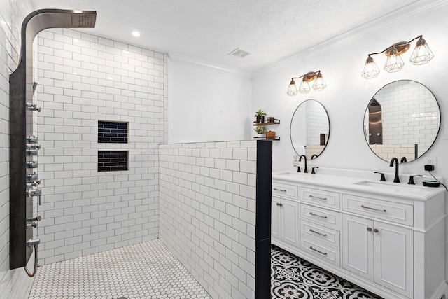 bathroom with crown molding, vanity, a textured ceiling, and tiled shower