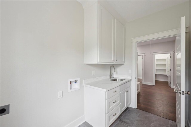 clothes washing area featuring baseboards, a sink, cabinet space, electric dryer hookup, and washer hookup