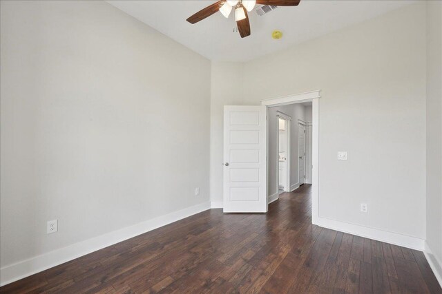 unfurnished room with baseboards, visible vents, a ceiling fan, and dark wood finished floors