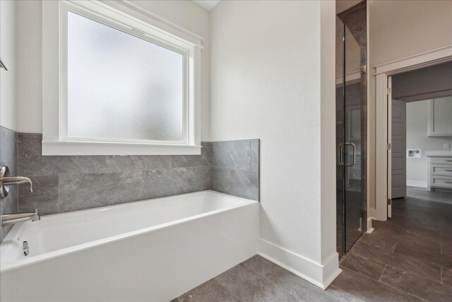 bathroom with baseboards, a garden tub, and a shower stall