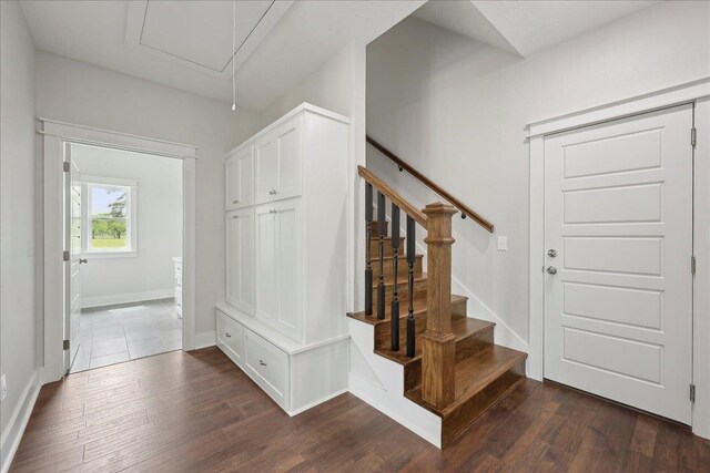 stairway with baseboards, wood finished floors, and attic access