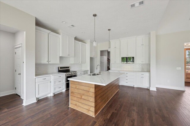 kitchen with range with two ovens, dark wood finished floors, a sink, visible vents, and white cabinets