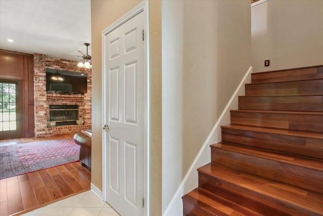 stairway featuring hardwood / wood-style flooring and a brick fireplace