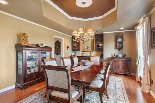 dining room featuring hardwood / wood-style floors, a tray ceiling, ornamental molding, and a chandelier