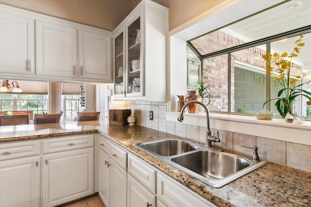 kitchen with white cabinetry, sink, and light stone counters