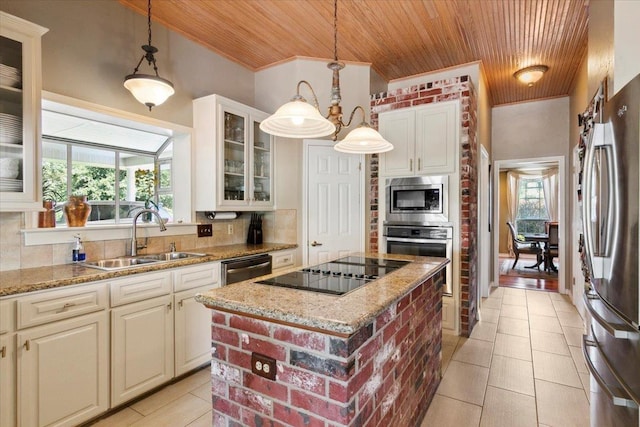 kitchen featuring stainless steel appliances, decorative light fixtures, a center island, and sink