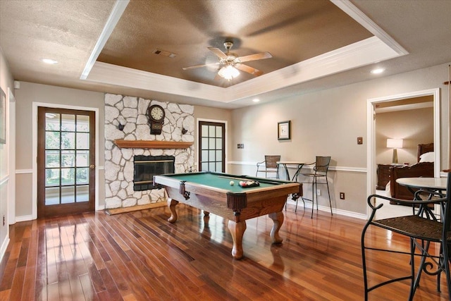 game room featuring a tray ceiling, a fireplace, ornamental molding, and wood-type flooring