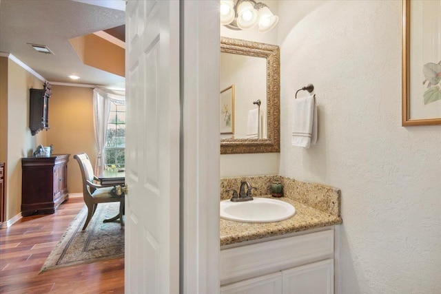 bathroom with vanity, crown molding, and wood-type flooring