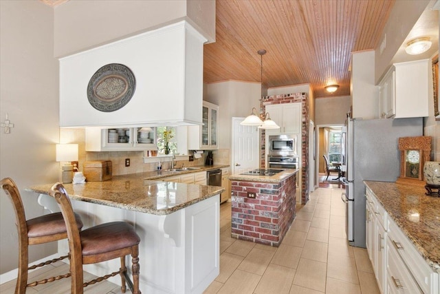 kitchen with decorative light fixtures, kitchen peninsula, white cabinets, stainless steel appliances, and backsplash