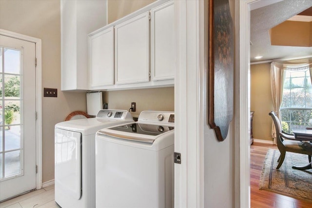 washroom featuring cabinets, separate washer and dryer, and light hardwood / wood-style flooring