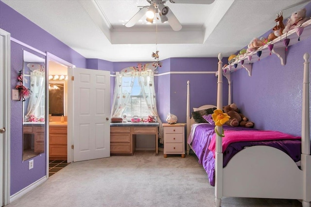 bedroom with ensuite bathroom, carpet flooring, ceiling fan, a tray ceiling, and crown molding