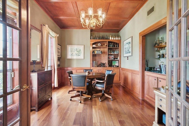 dining space with crown molding, hardwood / wood-style floors, wooden ceiling, and an inviting chandelier