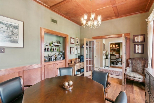 dining area featuring wooden ceiling, coffered ceiling, a chandelier, and light wood-type flooring