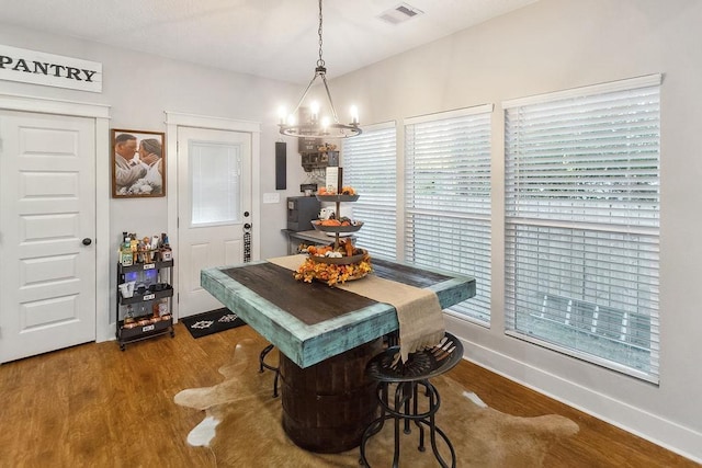 dining area with wood-type flooring and a notable chandelier