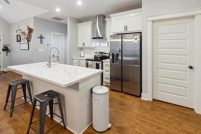 kitchen with stainless steel appliances, white cabinetry, wall chimney exhaust hood, and an island with sink