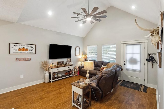 living room with hardwood / wood-style flooring, ceiling fan, and high vaulted ceiling