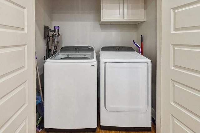 laundry room with cabinets, wood-type flooring, and washer and clothes dryer