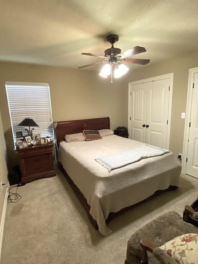 bedroom with ceiling fan, a closet, and light carpet