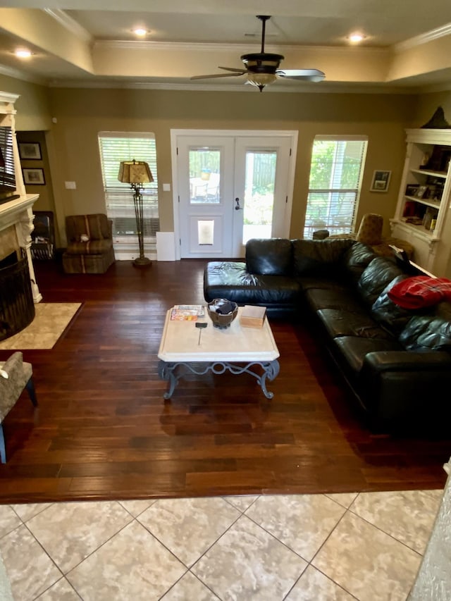 living room featuring french doors, a tray ceiling, ceiling fan, crown molding, and light hardwood / wood-style floors