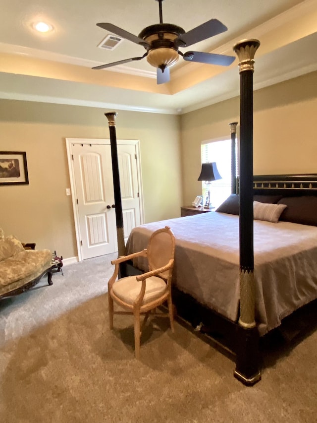 carpeted bedroom with ceiling fan, ornamental molding, and a tray ceiling