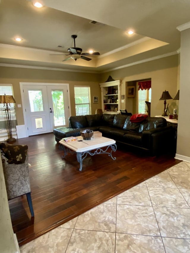 living room with french doors, a raised ceiling, ceiling fan, and a healthy amount of sunlight