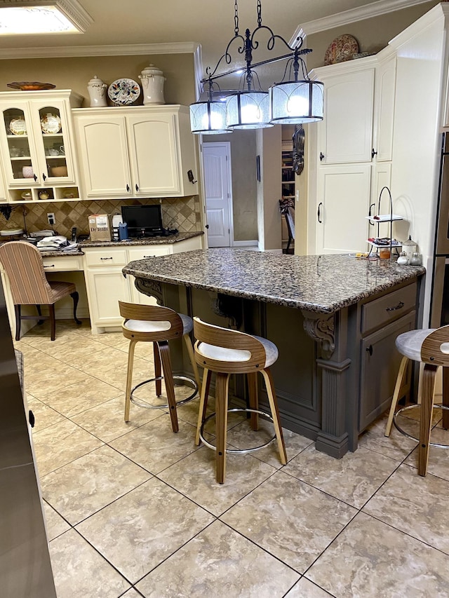 kitchen featuring white cabinetry, hanging light fixtures, dark stone counters, decorative backsplash, and ornamental molding