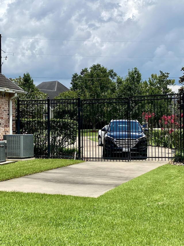 view of gate with a yard and cooling unit