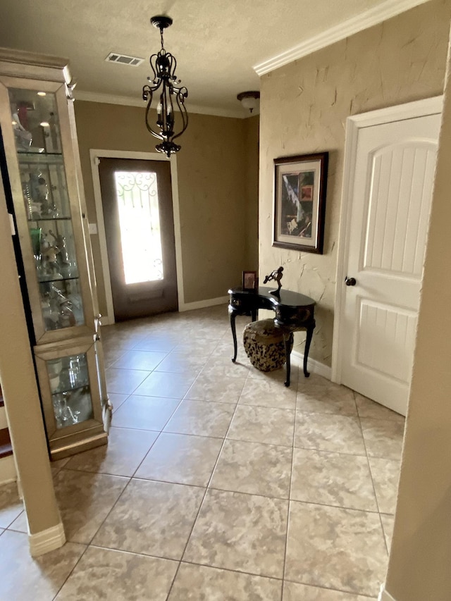 entrance foyer featuring light tile patterned floors, a textured ceiling, ornamental molding, and a notable chandelier