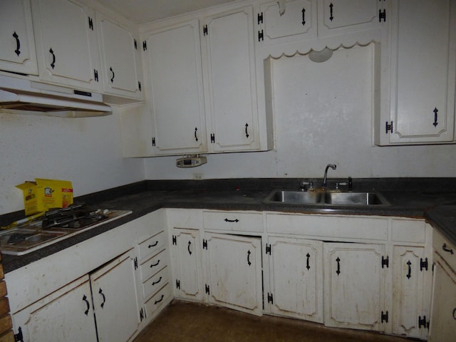 kitchen with dark tile patterned flooring, white gas stovetop, white cabinetry, and sink