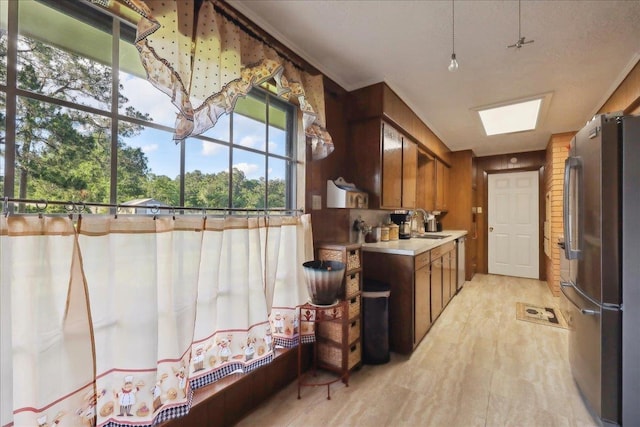 7760 Laurie Ln, Lumberton, TX 77657 - kitchen featuring stainless steel appliances, brown cabinetry, light countertops, light wood-style floors, and a sink