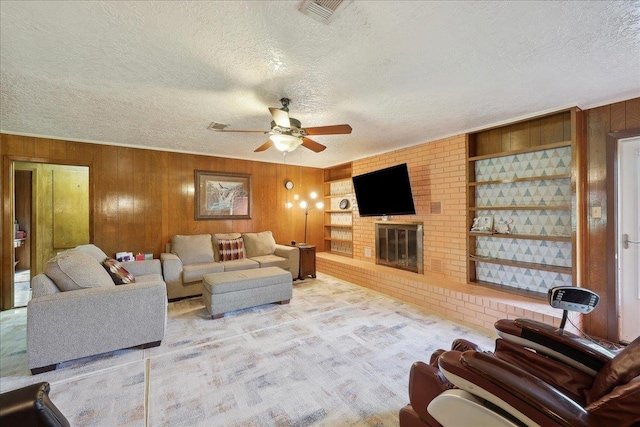 7760 Laurie Ln, Lumberton, TX 77657 - living room featuring a textured ceiling, wood walls, ceiling fan, a brick fireplace, and light carpet