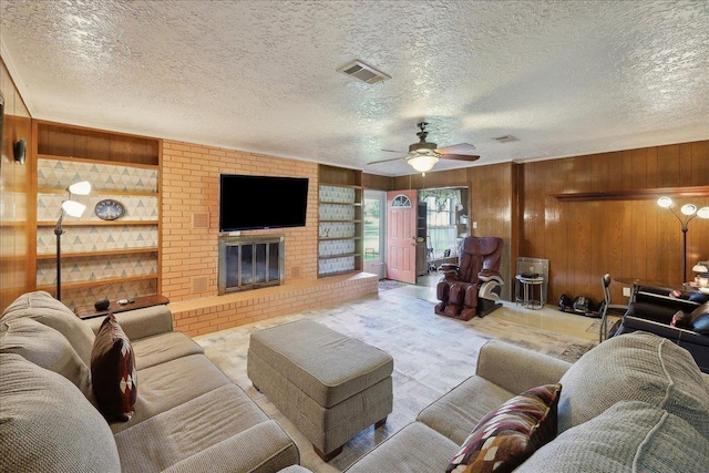7760 Laurie Ln, Lumberton, TX 77657 - living area with wood walls, built in features, ceiling fan, a textured ceiling, and a fireplace