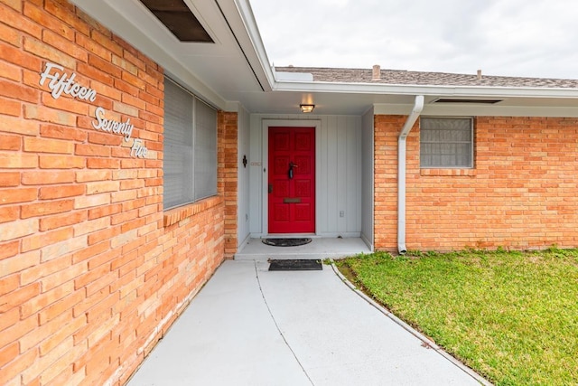 view of exterior entry featuring a lawn