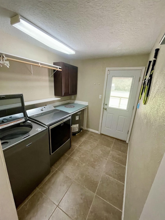 laundry area with cabinets, washer and dryer, and a textured ceiling