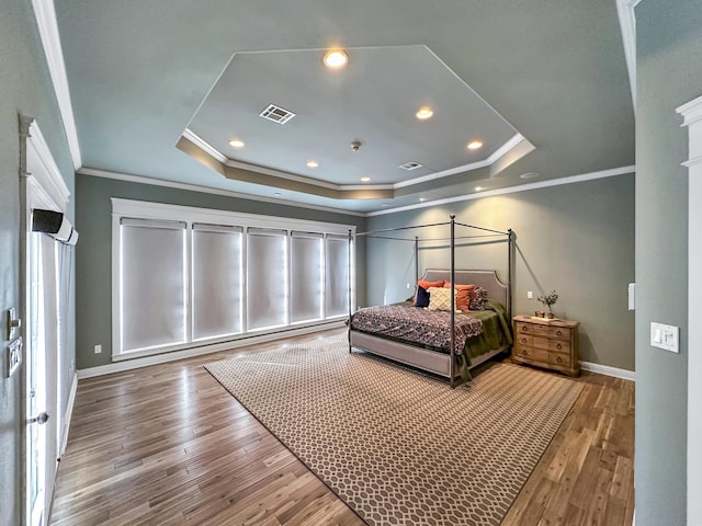 bedroom with crown molding, wood-type flooring, and a tray ceiling