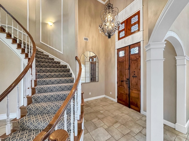 entrance foyer featuring ornate columns, an inviting chandelier, and a high ceiling