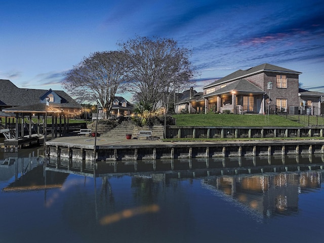 pool at dusk with a water view, a lawn, and a boat dock