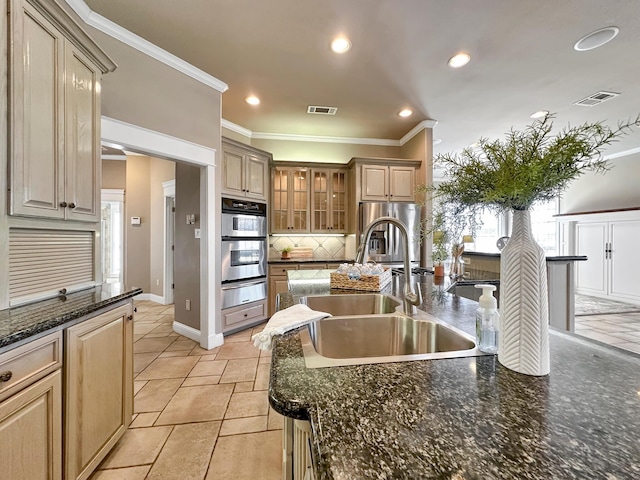 kitchen with sink, decorative backsplash, dark stone counters, stainless steel appliances, and crown molding