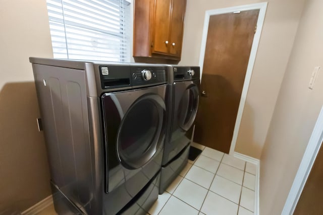 laundry area with washer and clothes dryer, light tile patterned flooring, and cabinets