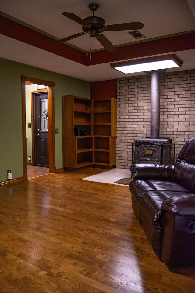 living room featuring a wood stove, ceiling fan, and hardwood / wood-style flooring